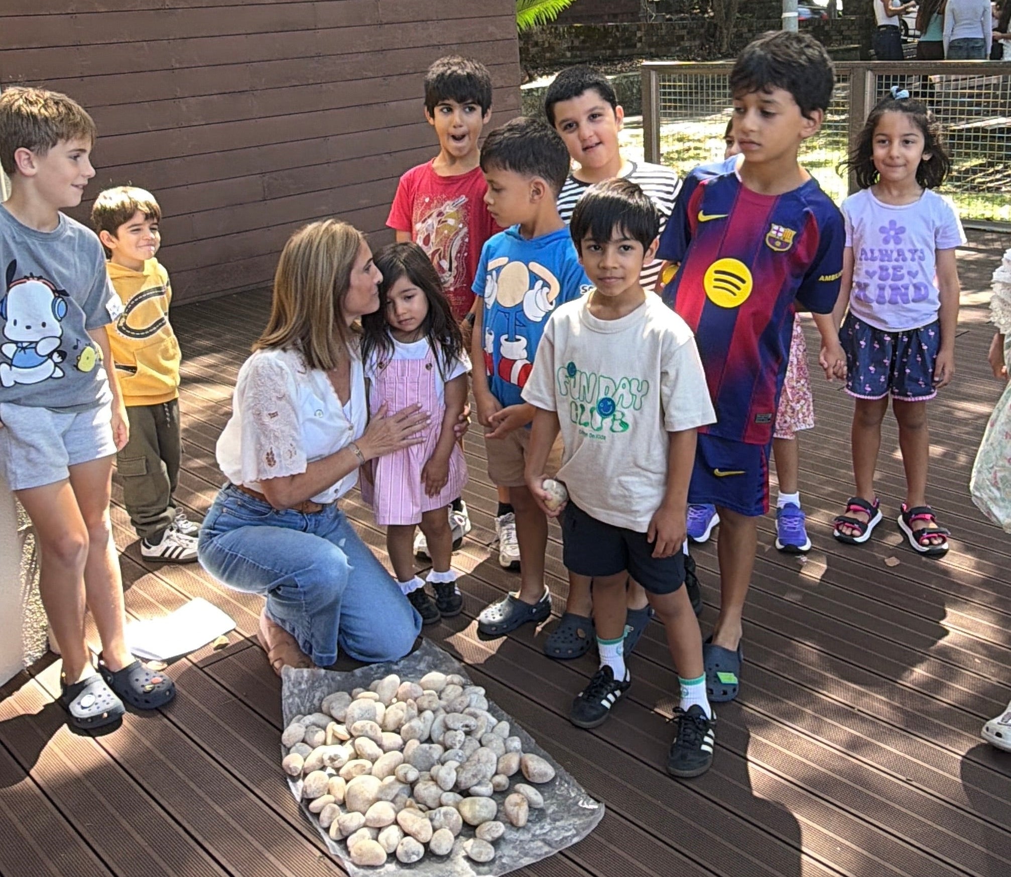 Woman with children outdoors on a wooden deck, surrounded by pebbles for stones for bondi rememberance.